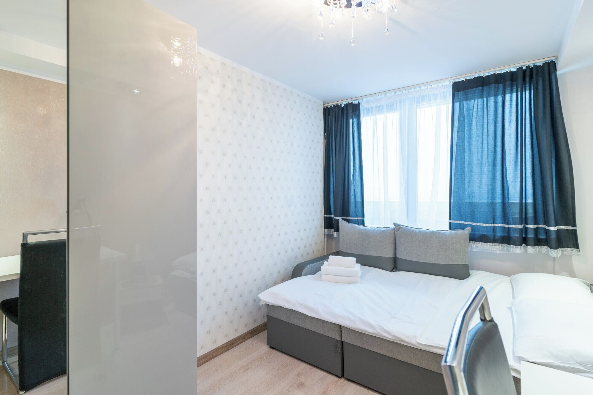 A modern bedroom with a bed, bedside tables, and a window with curtains.