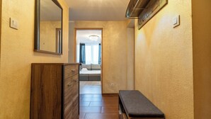 A narrow hallway with wooden flooring and walls, leading to a room with a bed and a window. - Park Śląski 18th Floor Apartment (Katowice)