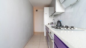 A narrow kitchen with a white countertop, a gas stove, and a sink. - Park Śląski 18th Floor Apartment (Katowice)