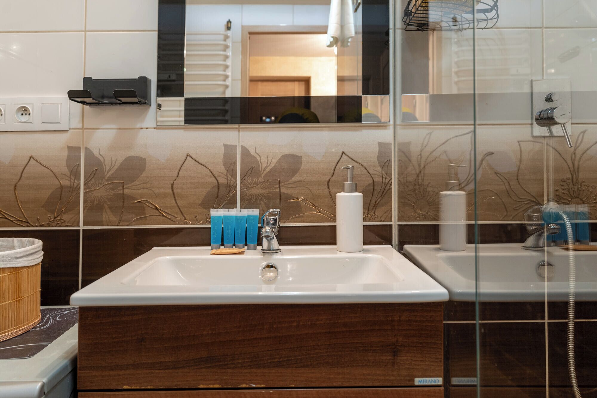 Une salle de bain avec un lavabo blanc, un miroir et un pare-feu décoratif.