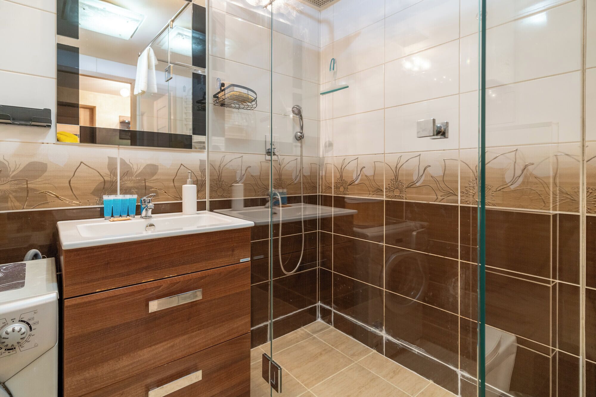 A modern bathroom with a glass shower enclosure, a wooden vanity, and a large mirror.