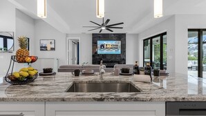 Una cocina moderna con encimera de granito, pileta de acero inoxidable y ventilador de techo.