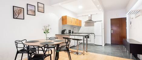 A modern kitchen with wooden cabinets, a central island, and a dining area with a round table and chairs.