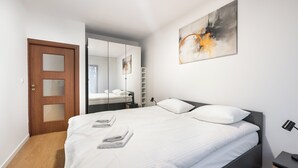 Ein modernes Schlafzimmer mit einem großen Bett, einer Holztür, einem Spiegel und einem Bild an der Wand.