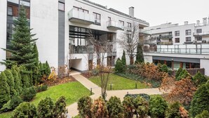 Ein modernes Gebäude mit mehreren Balkonen und einem gepflegten Garten.
