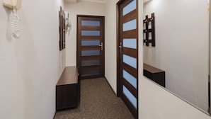 A hallway with a wooden door with glass panels, a telephone, and a mirror on the wall.