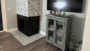 Ein Wohnzimmer mit Kamin, einem an der Wand montierten Fernseher und einer Vitrine.