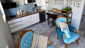 A modern kitchen with white cabinets, a wooden countertop, and a dining area with blue upholstered chairs and a wooden table.