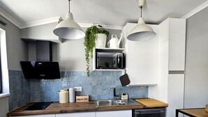 A modern kitchen with white cabinets, a black dishwasher, a wooden countertop, and a patterned floor.
