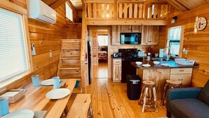 Ein gemütliches Blockhauss-Interieur mit Holztisch, Küchenzeile und Deckenventilator.