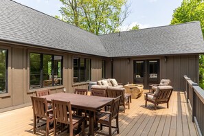 Eine Terrasse mit einem Holztisch und Stühlen, einer Couch und einem kleinen runden Tisch.