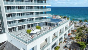 Un hôtel moderne doté d’un salon sur le toit, de grandes fenêtres et offrant une vue sur l’océan.