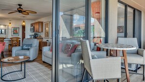 Een moderne woonkamer met een bank, fauteuils, een salontafel en een plafondventilator.