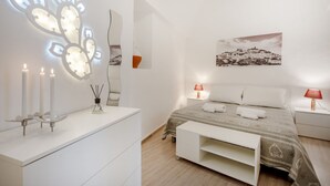 A modern bedroom with a bed, bedside tables, a nightstand, a mirror, and wall art. - GuestHost - Lovely apartment equipped with every comfort for 2 people and located in a typical stone building, of which it retains striking features in the internal architecture, such as the characteristic stone vault in the living area. The flat is loca (Ostuni)