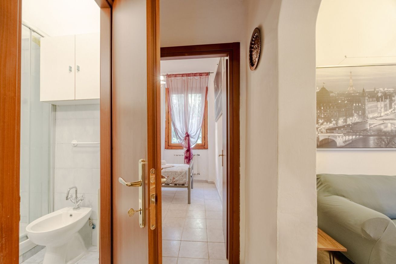 Une chambre avec un lit, une fenêtre avec des rideaux, un lavabo et une vue sur le paysage urbain.