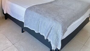 Une chambre à coucher avec un lit, des rideaux blancs et une armoire.