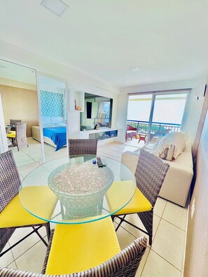 Un salon moderne avec une table basse en verre, des meubles en osier, un canapé et un balcon avec vue.