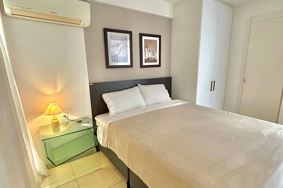 Une chambre à coucher avec un lit, une table de chevet avec une lampe, deux tableaux encadrés au mur et une armoire.
