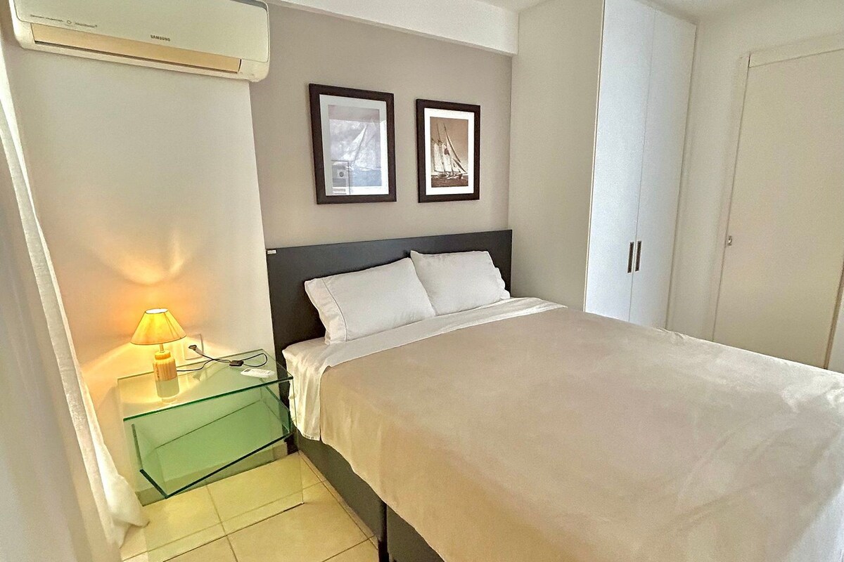 Una camera da letto con un letto, un comodino con una lampada, due quadri appesi al muro e un armadio.