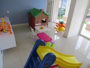 A children's play area with a slide, playhouse, and tables.