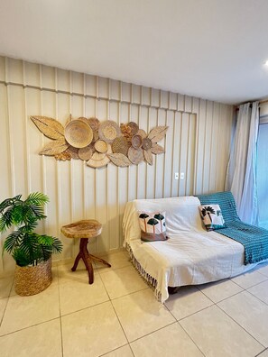 A bedroom with a bed, a wall art piece, a small table, and a potted plant.
