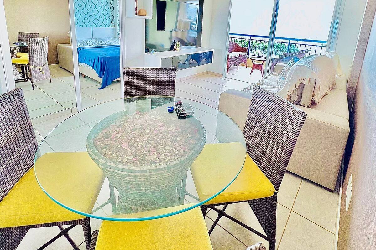 Un salon moderne avec une table basse en verre, des meubles en osier, un canapé et un balcon avec vue.