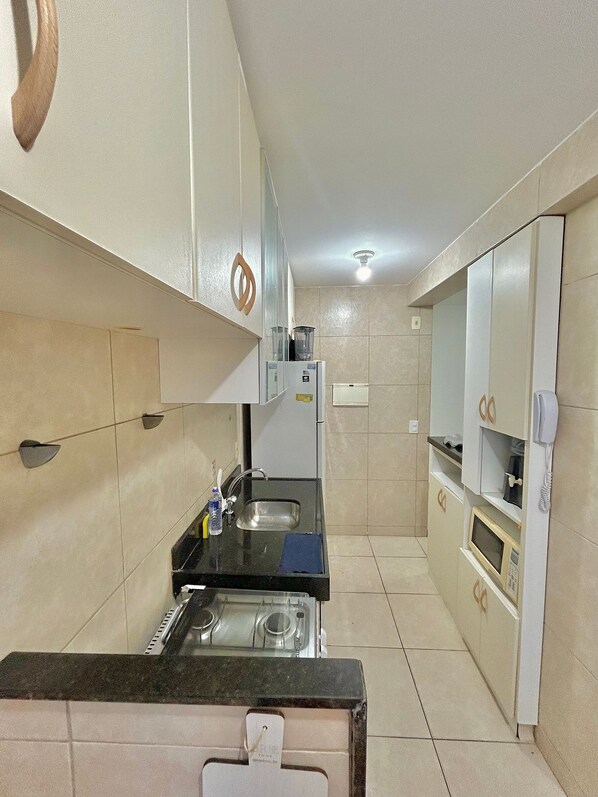 A compact kitchen with a gas stove, two sinks, and a microwave.