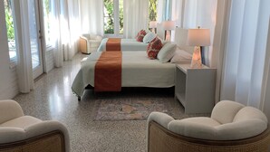 A hotel room with two beds, a ceiling fan, and a view of greenery outside. - Siesta Home, A Serene Retreat (Sarasota)