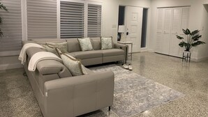 A modern living room with a beige sofa, a small side table, and a grey rug. - Siesta Home, A Serene Retreat (Sarasota)