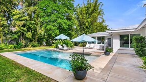 A modern house with a swimming pool, outdoor seating, and lush greenery. - Siesta Home, A Serene Retreat (Sarasota)