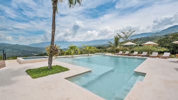 Una piscina al aire libre, sombrillas, sillones reclinables de piscina