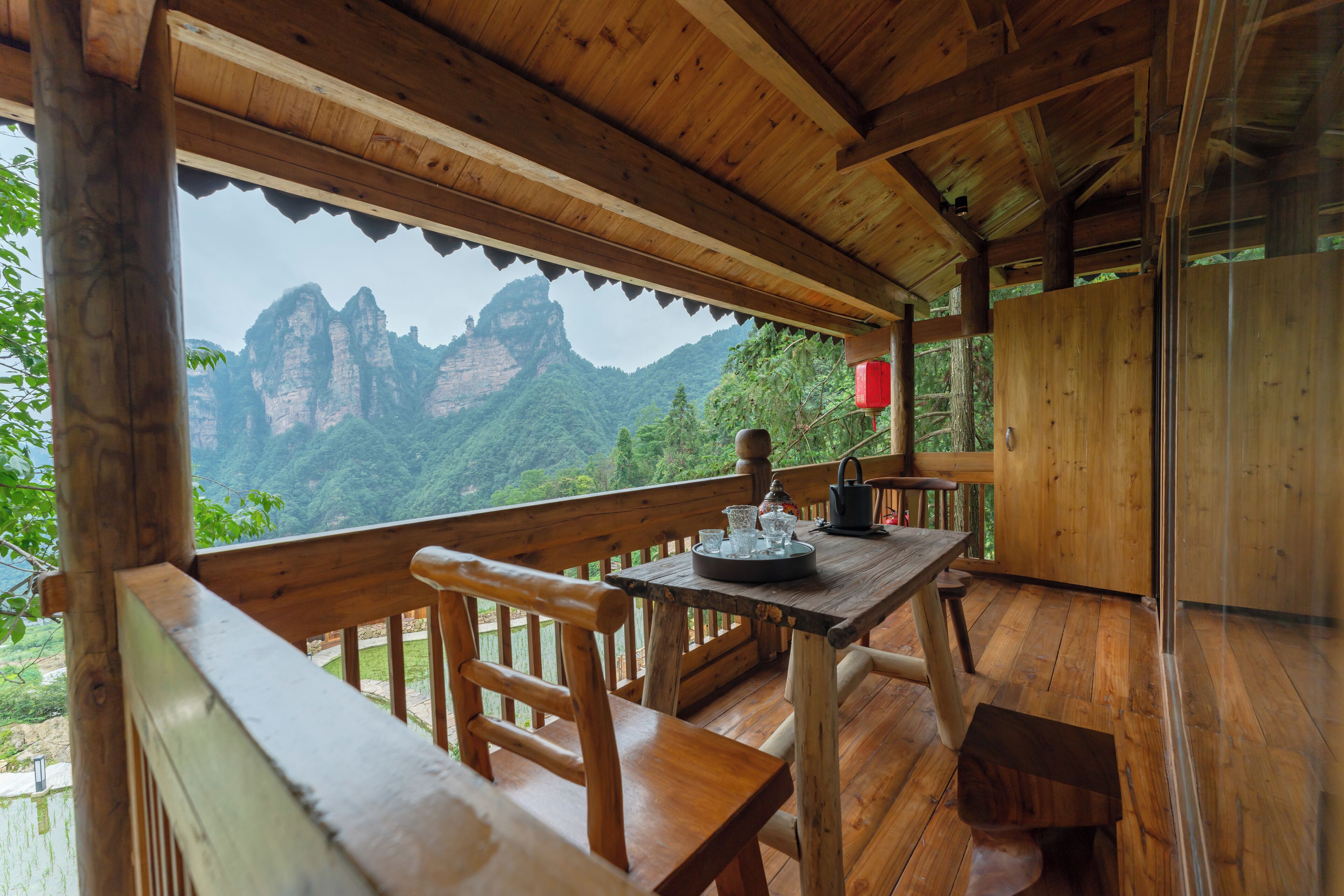 A wooden deck with a table and chairs, overlooking a mountainous landscape.