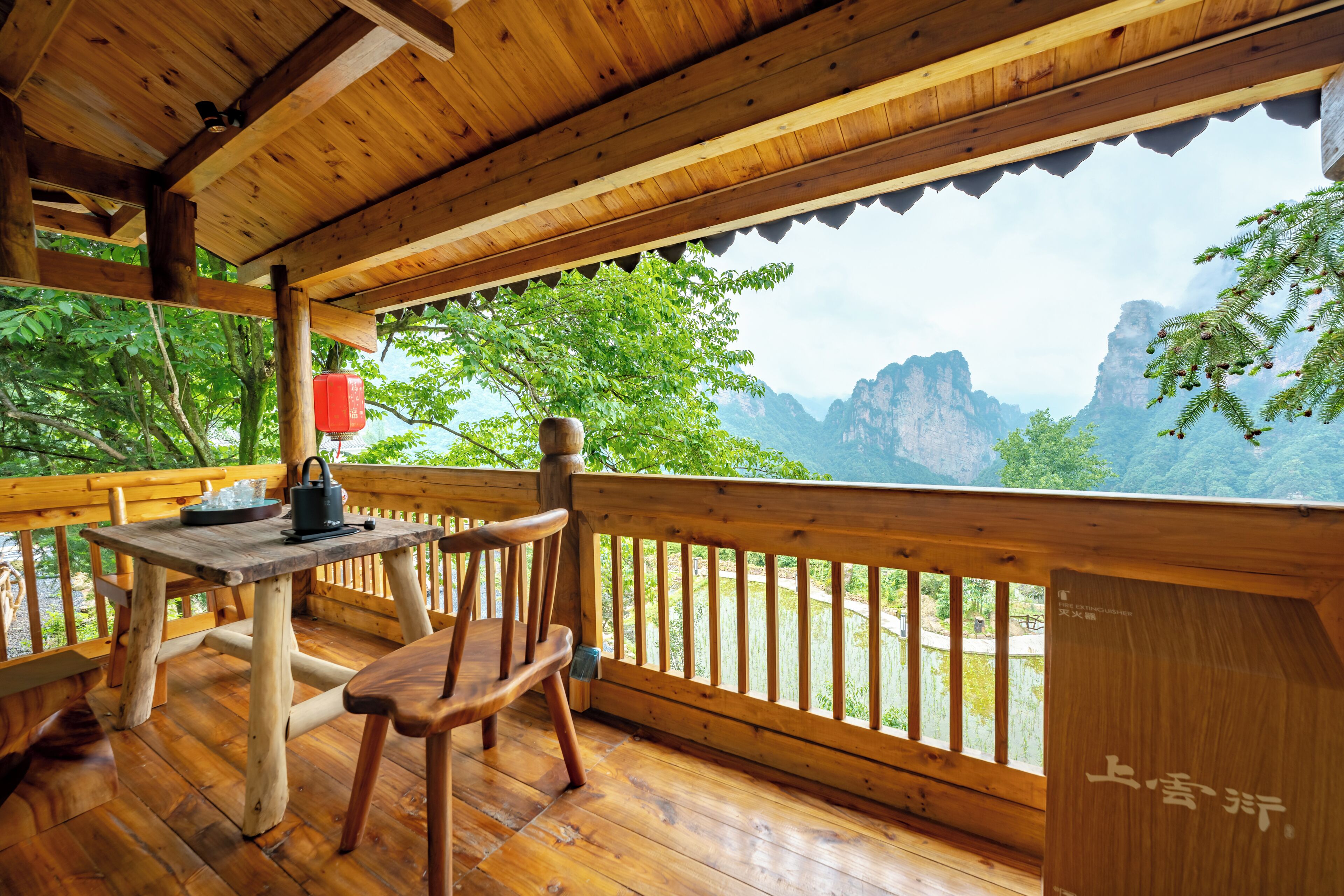 Una terraza de madera con una mesa y sillas, con vistas a un paisaje montañoso.