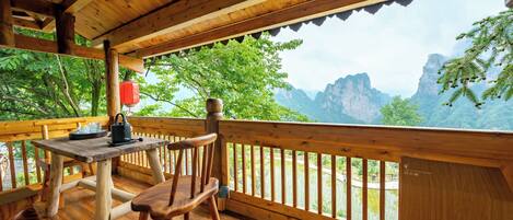 Una terraza de madera con una mesa y sillas, con vistas a un paisaje montañoso.