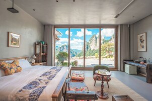 Un dormitorio con un ventanal grande, una cama, un escritorio y una silla.