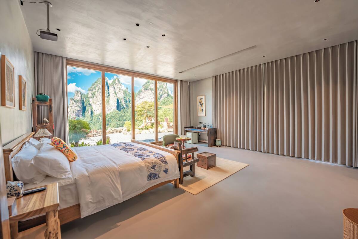 Un dormitorio moderno con una cama grande, un escritorio y vistas a montañas.