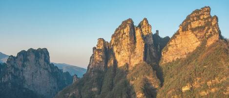 A mountainous landscape with prominent rock formations and a clear sky.