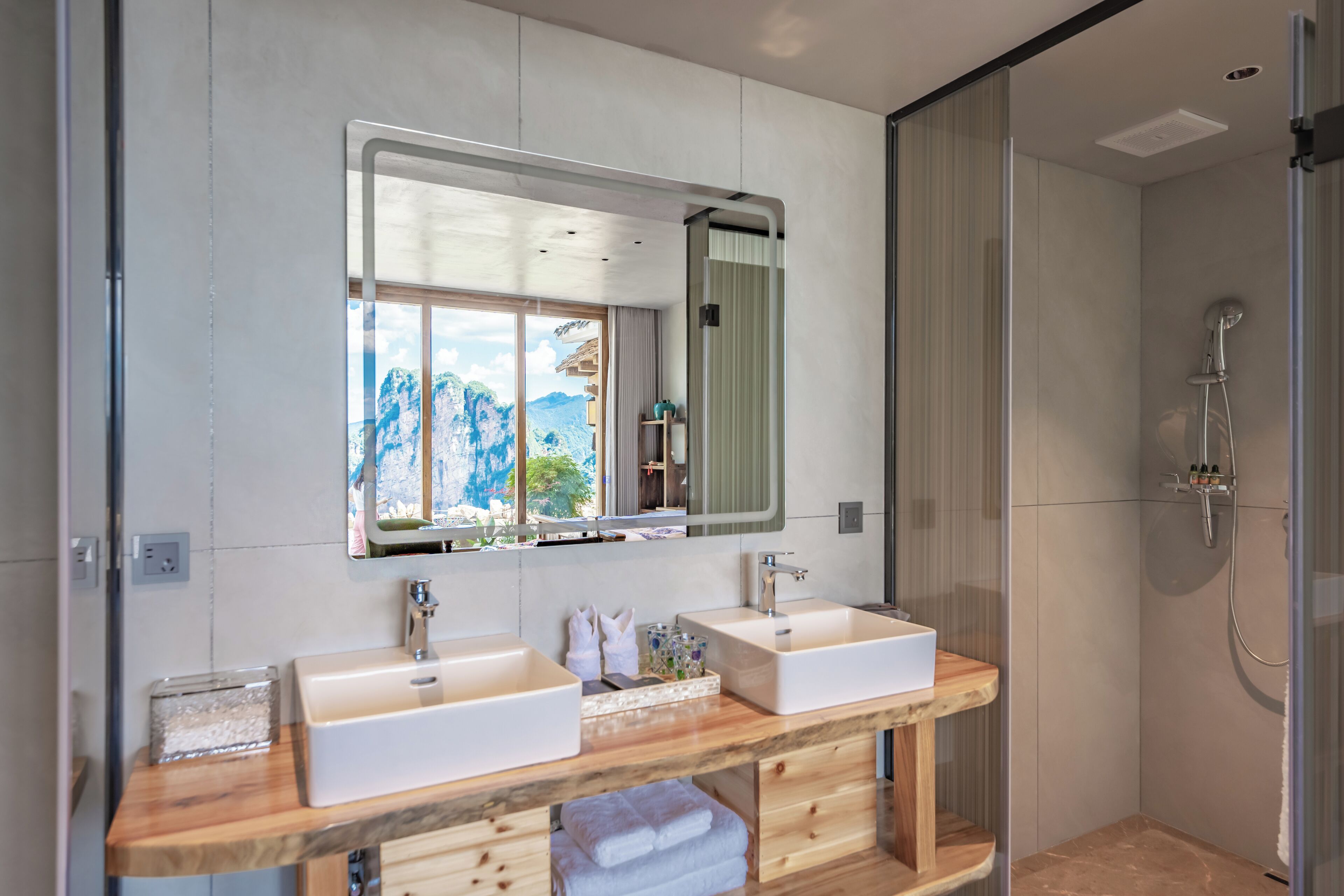 A modern bathroom with two sinks, a large mirror, and a shower.