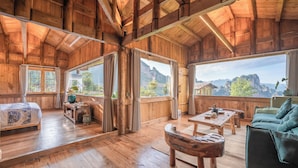 Eine Holzhütte mit einem Bett, einem Sofa, einem Tisch und Bergblick.