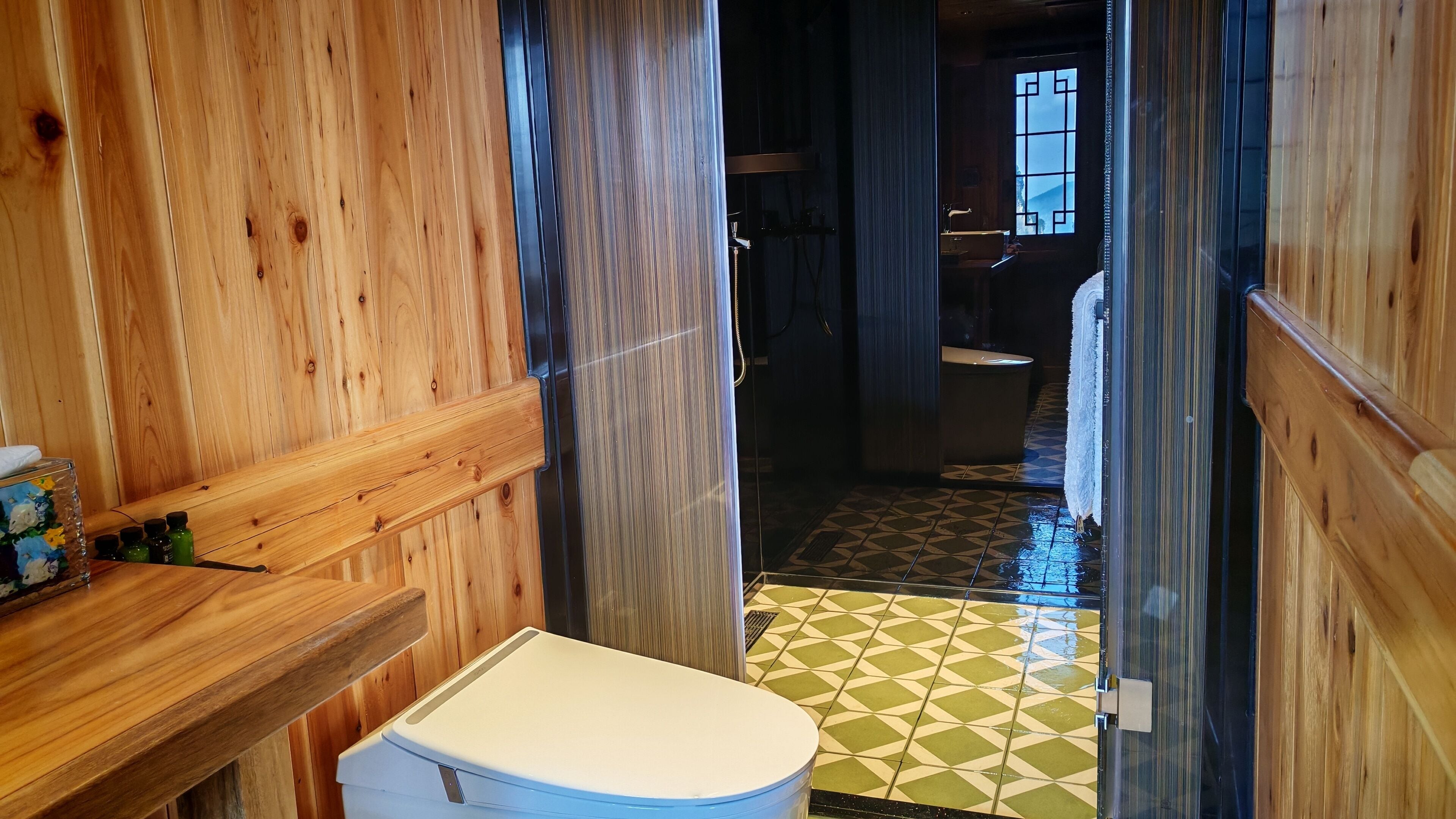 Baño de cabaña de madera con inodoro, lavamanos y zona de ducha.