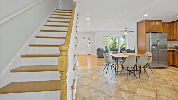 Una cocina moderna con comedor, escalera de madera y vistas al exterior.