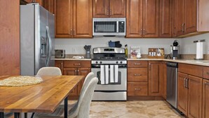 Una cocina con armarios de madera, un refrigerador de acero inoxidable, un microondas, un horno y un lavavajillas.