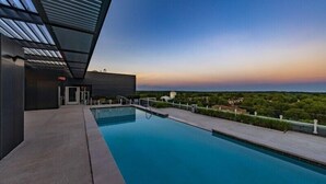 A modern pool area with a clear view of the surrounding landscape and a building with a sloped roof.