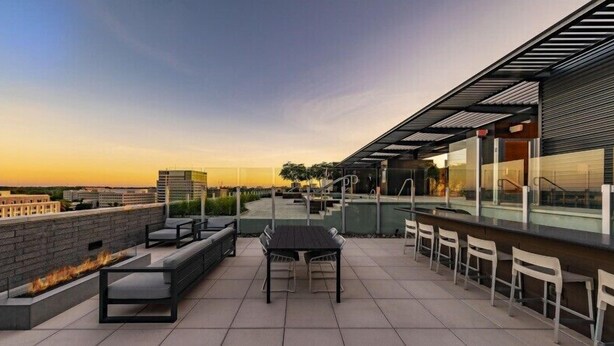 A rooftop terrace with a fire feature, seating, and a bar area.