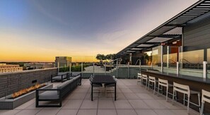 A rooftop terrace with a fire feature, seating, and a bar area.