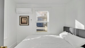 Une chambre à coucher avec un lit, une fenêtre et un appareil de climatisation.