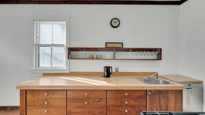 Une cuisine avec un plan de travail en bois, un évier, une cuisinière et une horloge au mur.