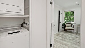 A laundry room with a front-loading washer and dryer, a door leading to a room with a window and a chair. - 3 Bd 2 1/2 bath Chic Large.30mto DC, 12min to IDA (Herndon)