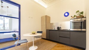 Een moderne keuken met een eethoek, een groot raam en een glazen deur met blauwe lijst.