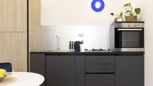 Een moderne keuken met een inbouwoven, een koffieapparaat en een mand met planten op het aanrecht.